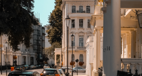 A sunny street in london with cars parked on the road