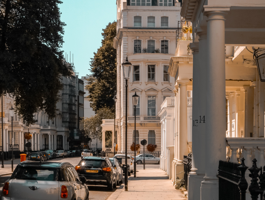 A sunny street in london with cars parked on the road