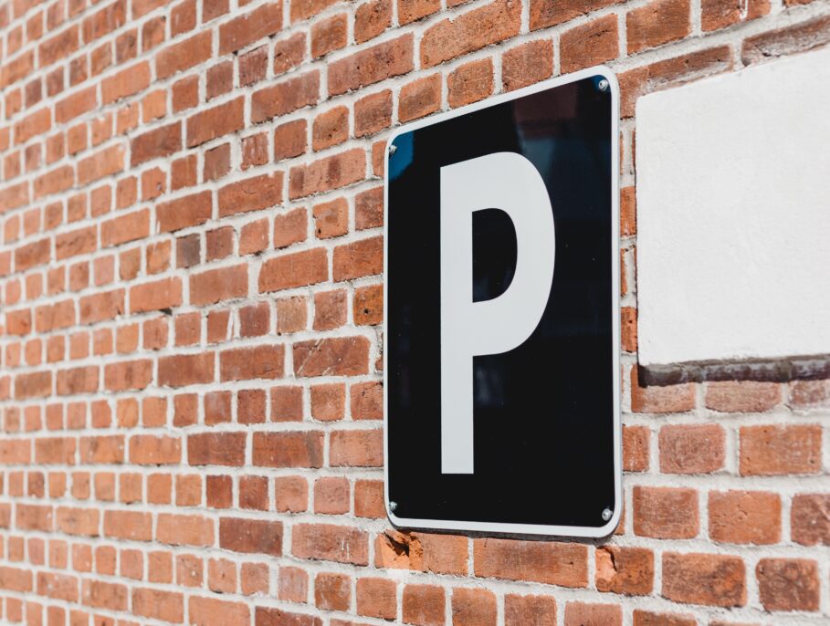 Black parking sign on a brick wall