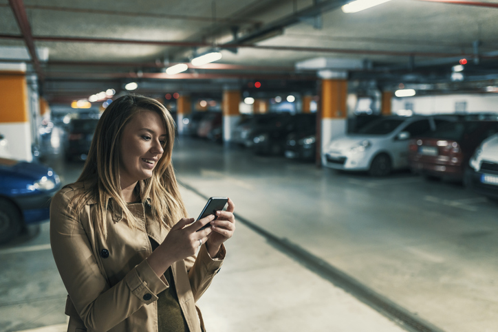 Woman checking her phone in a parking lot