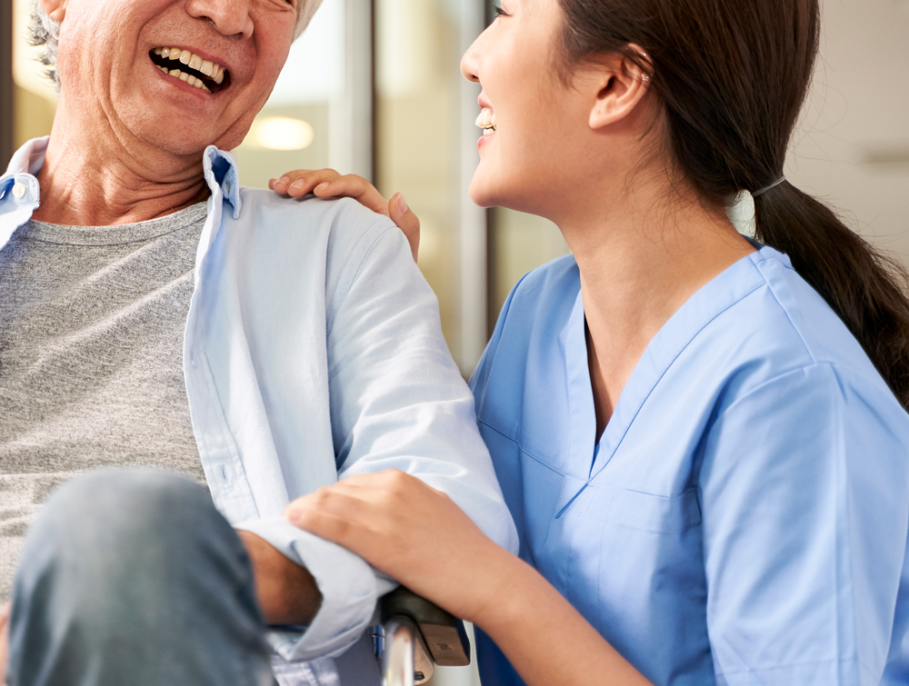 Doctor supports & laughs with man in a wheelchair