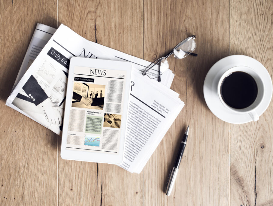 Newspaper with tablet on wooden table