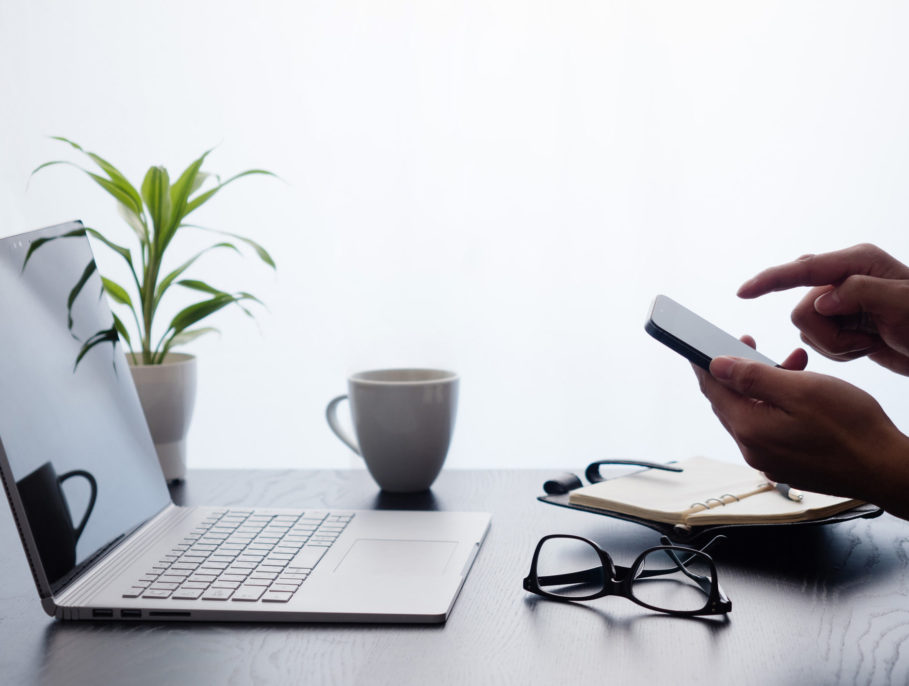 Woman using a phone in front of a laptop